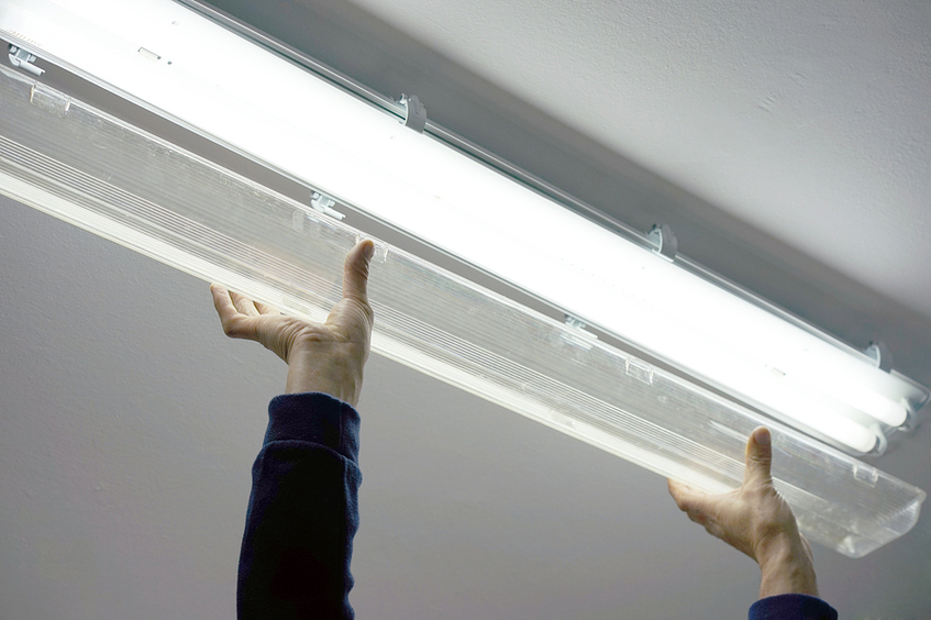 Person fixing overhead lighting.